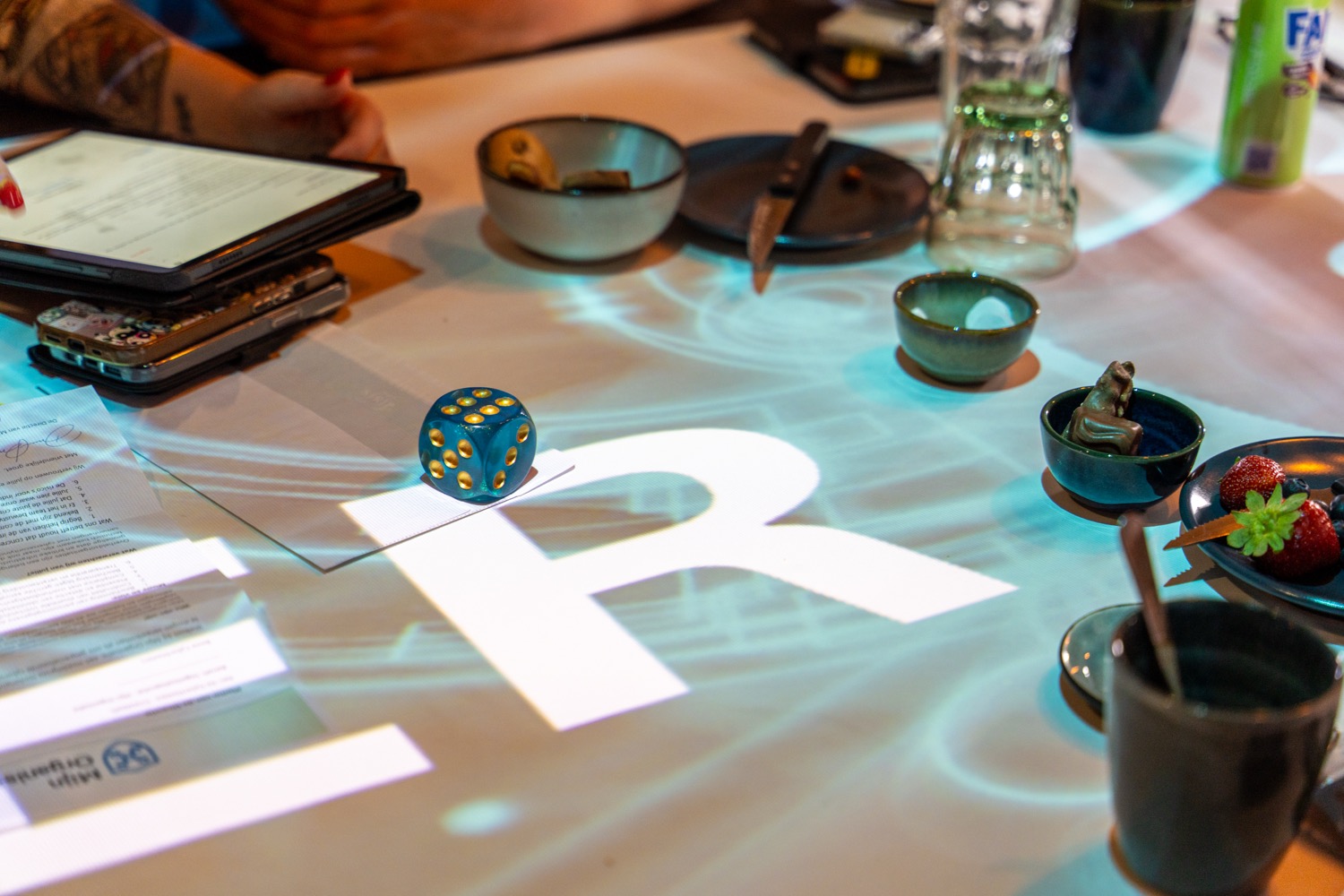 Sfeerimpressie ransomware-simulatie: dobbelsteen en R-projectie op tafel.